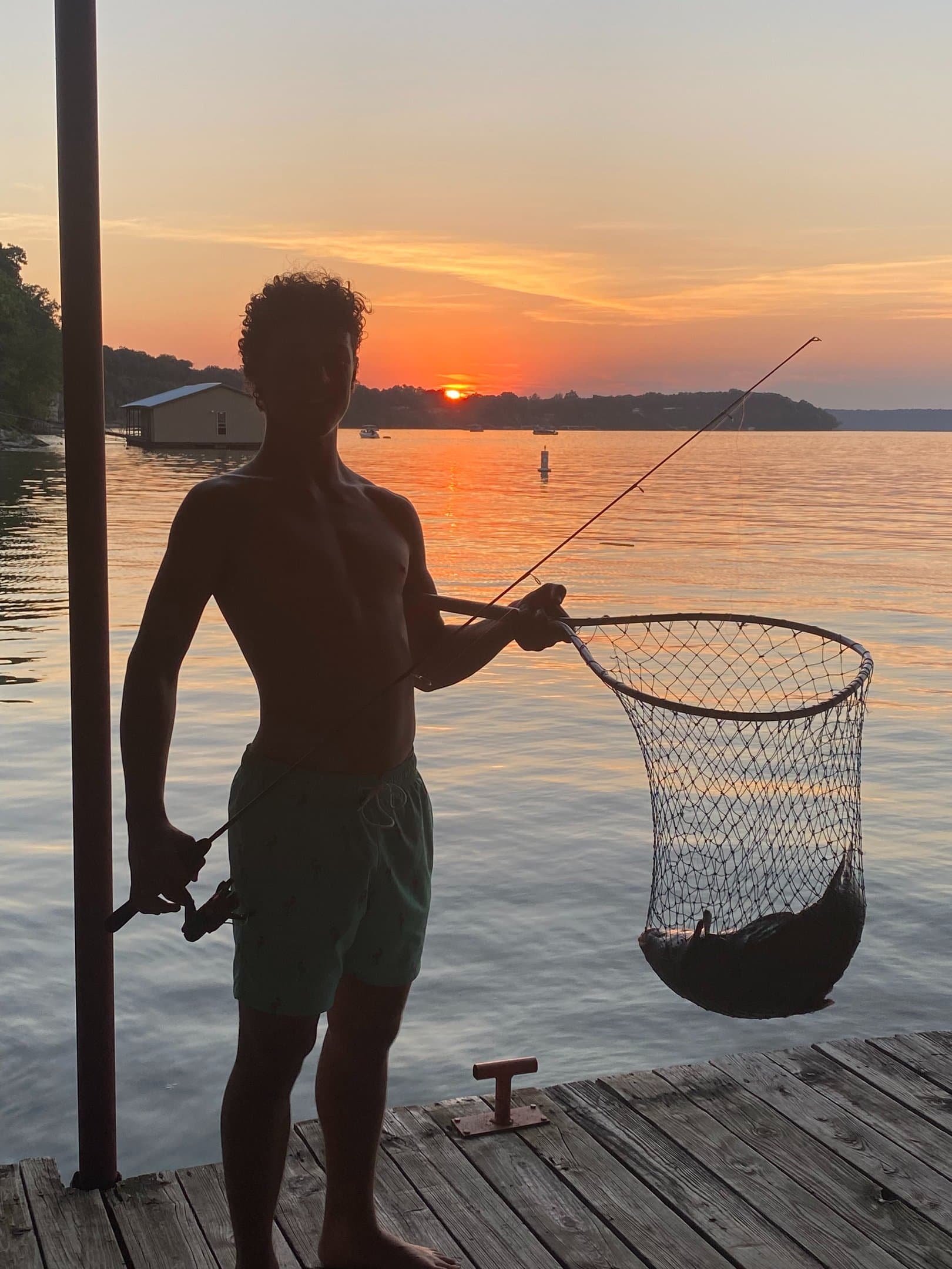 A guest on the dock at sunset with a fishing net