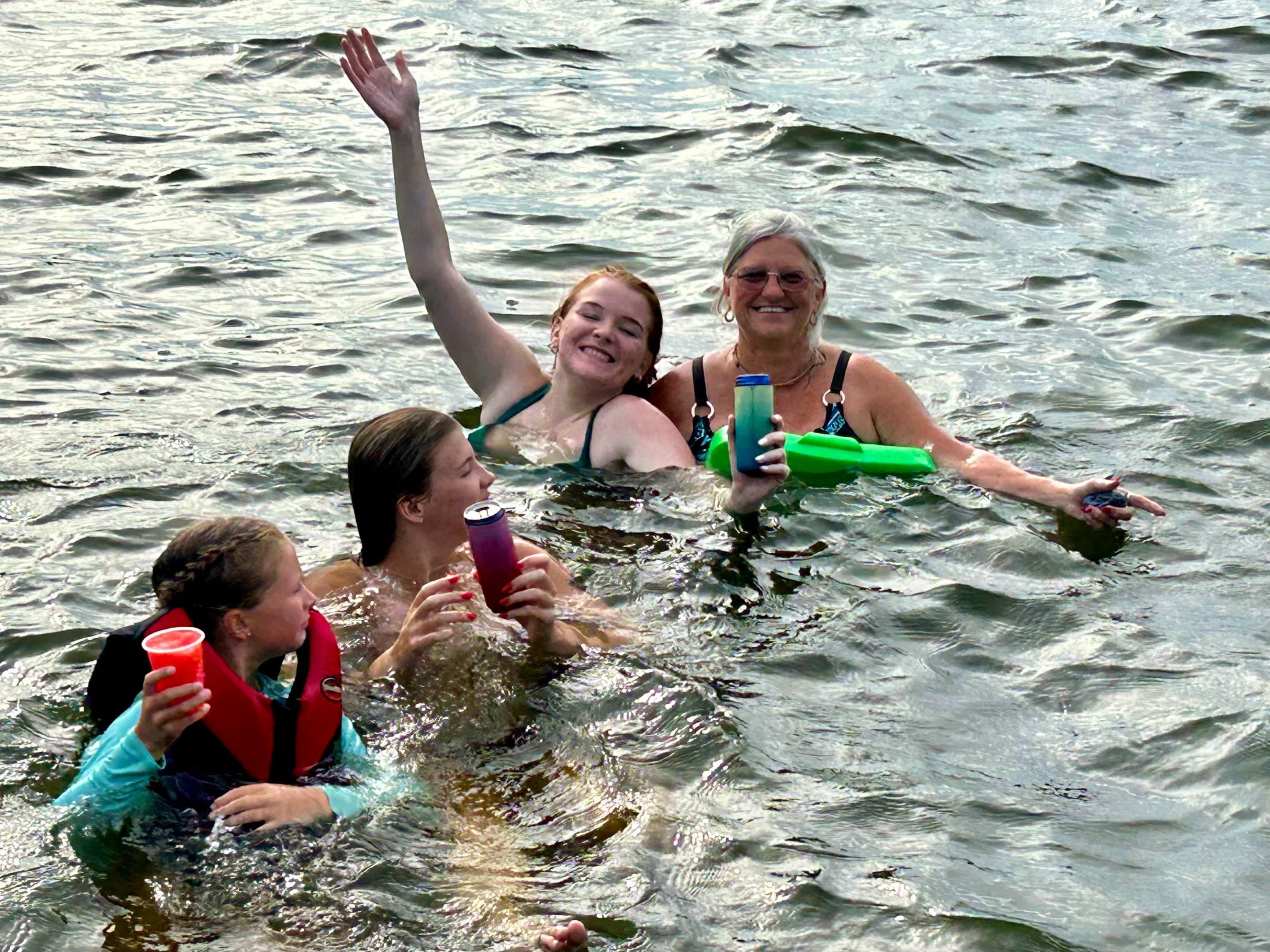 A family swimming in the lake near the dock, kids in life vests