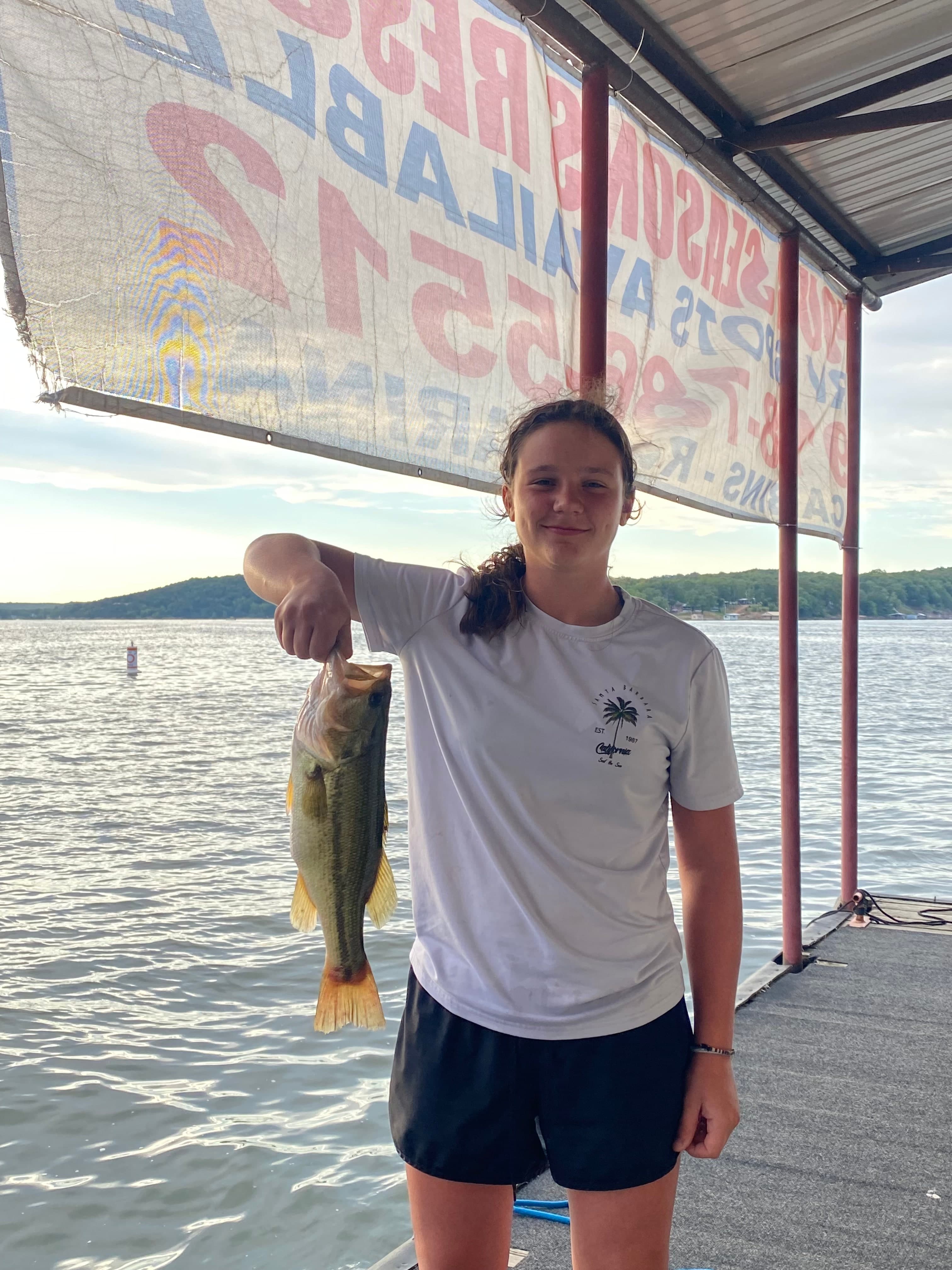 A guest on the dock at sunset with a largemouth bass